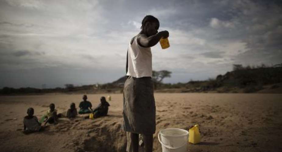 A Turkana woman drinks from a bucket of water she scooped in a dry river bed in Lodwar on March 13, 2014.  By Marco Longari AFPFile