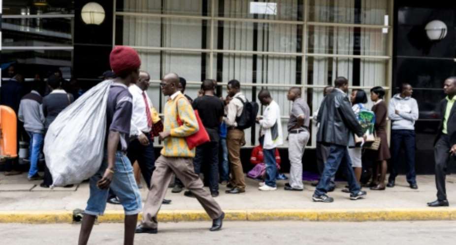 Due to Zimbabwe's crippling cash shortage, banks limit withdrawals meaning that long queues of people waiting outside are a common sight.  By ZINYANGE AUNTONY AFPFile