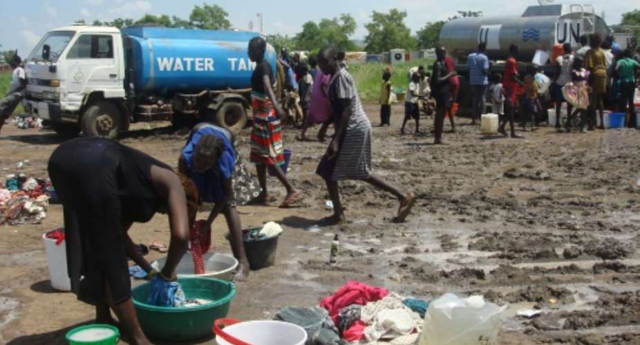This handout photo provided by the United Nations Mission in the Republic of South Sudan and released on July 16, 2016 shows women doing laundry as people collect water at the UN compound in the Tomping area in Juba.  By Beatrice Maregwa AFPFile
