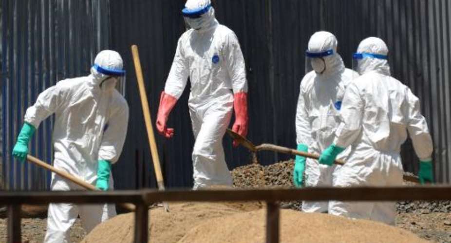 Workers from the Liberian Red Cross at ELWA 2 Ebola management center in Monrovia on October 23, 2014 shovel sand which will be used to absorb fluids emitted from the bodies of Ebola victims.  By Zoom Dosso AFP