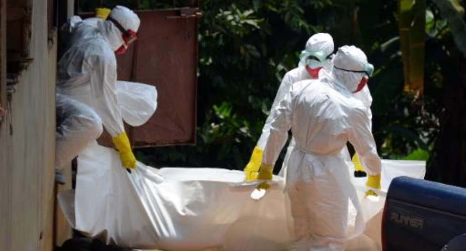 Liberian Red Cross health workers, wearing protective suits, carry the body of a 18-old-month baby, victim of the Ebola virus in a district of Monrovia on September 12, 2014.  By Zoom Dosso AFPFile