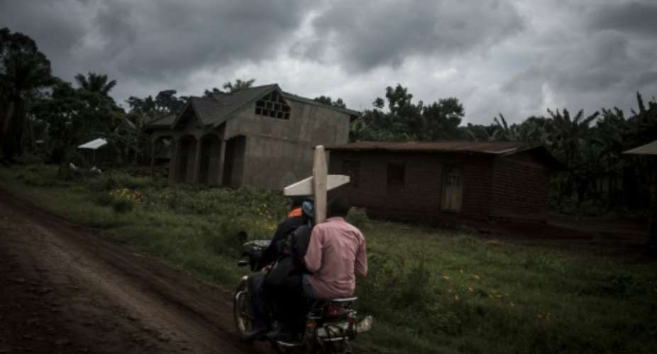 Ebola death: Three people riding a motorbike on a road near Beni carry a cross for a grave.  By John WESSELS AFP
