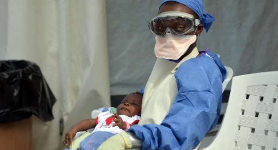A Liberian health worker holds a baby infected with the Ebola virus at the NGO Medecins Sans Frontieres Doctors Without Borders Ebola treatment center in Monrovia on October 18, 2014.  By Zoom Dosso AFPFile