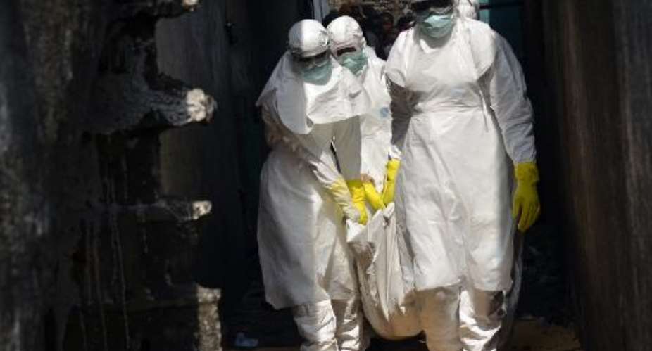 Red cross workers, wearing protective suits, carry the body of a person who died from Ebola in Monrovia, on January 5, 2015.  By Zoom Dosso AFPFile