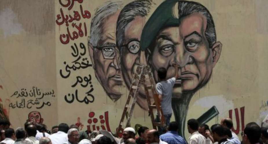 A man puts the finishing touches on graffiti of Egyptian leaders in Cairo.  By Mahmud Hams (AFP)