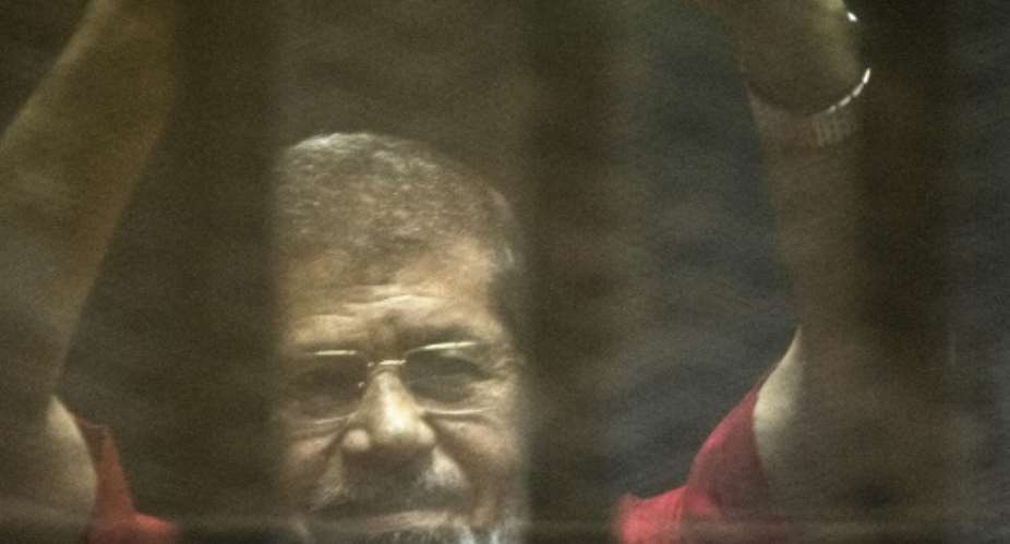 Egypt's ousted Islamist president Mohamed Morsi stands behind bars during his trial at the police academy in Cairo, on May 7, 2016.  By Khaled Desouki AFP