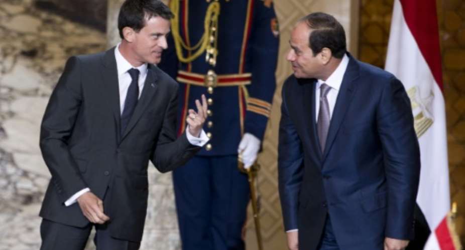 French Prime Minister Manuel Valls L gestures next to Egyptian president Abdel Fattah al-Sisi during a ceremony to sign military contracts at the presidential palace in Cairo on October 10, 2015.  By Kenzo Tribouillard AFP