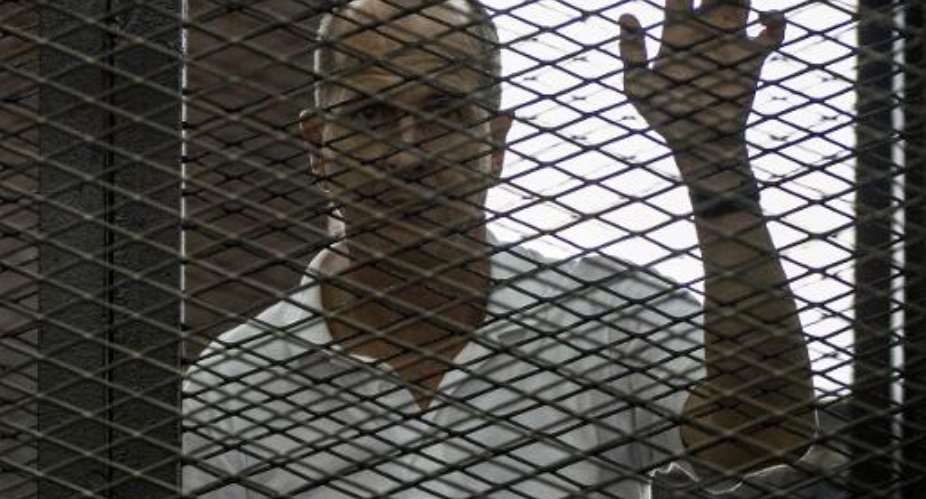 Australian Al-Jazeera journalist Peter Greste listens to the verdict in Cairo on June 23, 2014 inside the defendants cage during his trial for allegedly supporting the Muslim Brotherhood.  By Khaled Desouki AFPFile