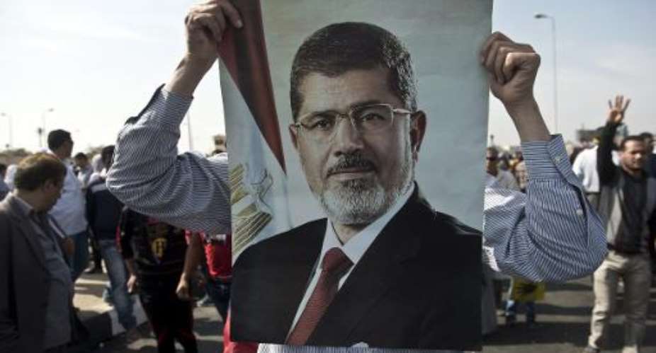 A supporter of the Muslim Brotherhood and of ousted president Mohamed Morsi holds a poster of Morsi during a rally outside the Police Academy where his trial is taking place in Cairo on November 4, 2013.  By Khaled Desouki AFPFile
