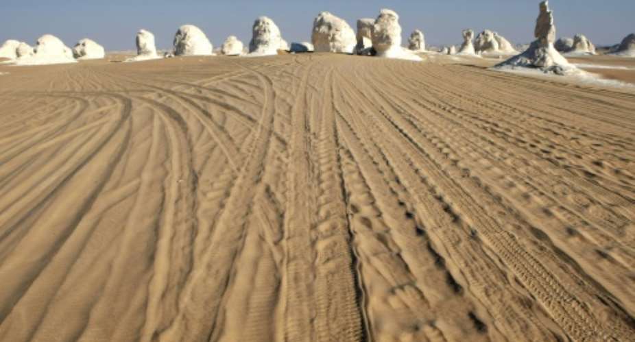 Off-road vehicle tracks mark the sand approaching a group of mushroom-like chalk Inselbergs in the White Desert, which lies within the Western Desert, September 2, 2015, in Egypt.  By Cris Bouroncle (AFP/File)