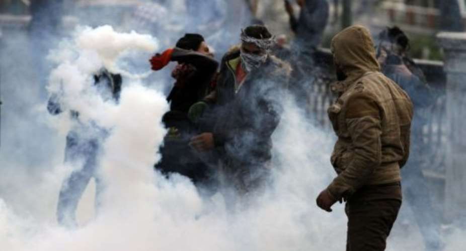 An Egyptian protester throws a tear gas canister back towards riot police during clashes in Cairo on January 29, 2013.  By Mohammed Abed AFP