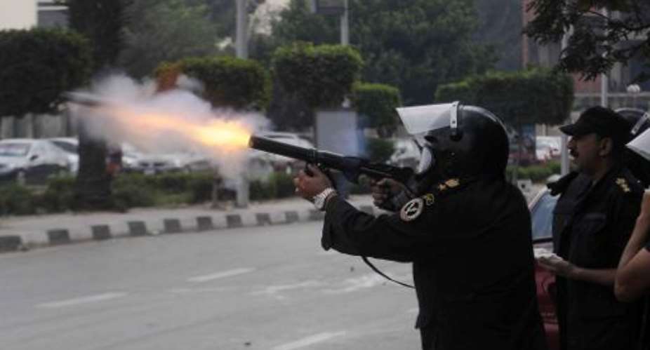 An Egyptian riot policeman fires a tear gas cannister towards demonstrating students of al-Azhar University who support the Muslim Brotherhood during clashes outside their campus in Cairo on December 9, 2013.  By Tarek Wajeh AFP