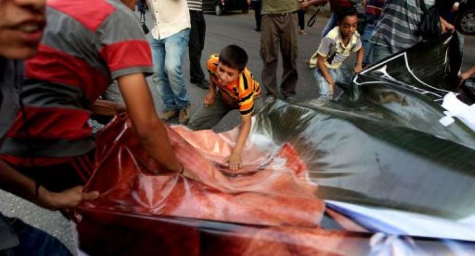 Egyptian protesters hit with their hands a ripped poster of presidential candidate Ahmed Shafiq.  By Marwan Naamani (AFP)