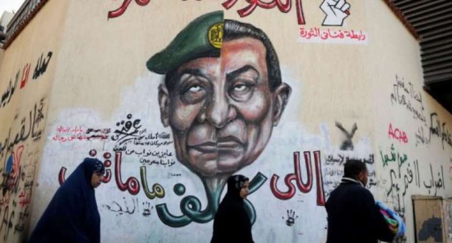 Egyptians walk past graffiti with a slogan reading, The revolution continues in Tahrir Square.  By Mohammed Hossam AFPFile