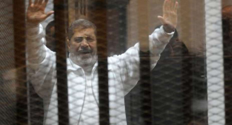 Egypt's deposed Islamist president Mohamed Morsi waves from inside the defendants cage during his trial at the police academy in Cairo on January 8, 2015.  By  AFPFile