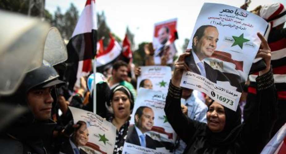 Egyptians hold portraits of President Abdel Fattah al-Sisi in front of the presidential palace of Ethadya in the capital Cairo on June 8, 2014.  By Mohamed el-Shahed AFPFile