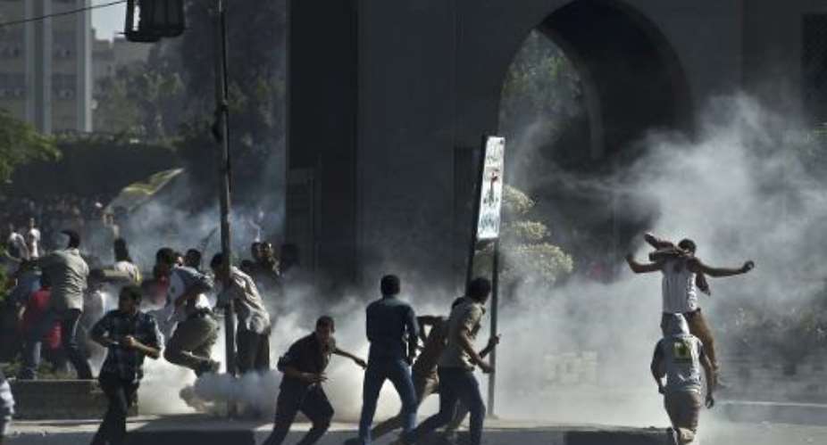 Students from Cairo's al-Azhar University run for cover from tear gas canisters fired by riot police during an anti-army protests outside their campus on October 20, 2013.  By Khaled Desouki AFPFile
