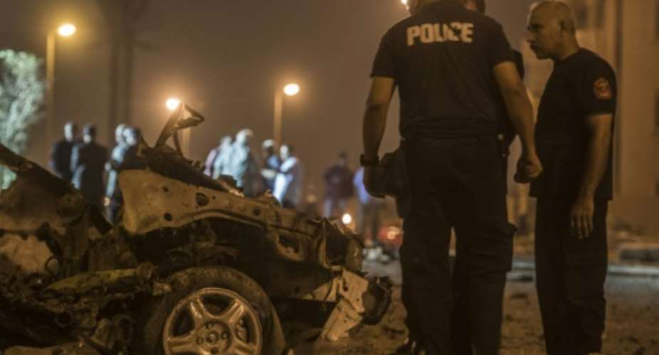 Egyptian policemen inspect the wreckage of a car bomb that exploded in a Cairo suburb after Egypts deputy prosecutor general drove by  wounding a passerby.  By Khaled Desouki (AFP/File)
