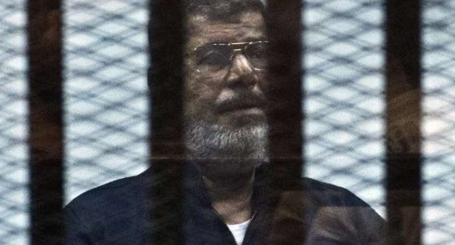 Egypt's ousted Islamist president Mohamed Morsi stands behind bars during his trial in Cairo on June 16, 2015.  By Khaled Desouki AFPFile