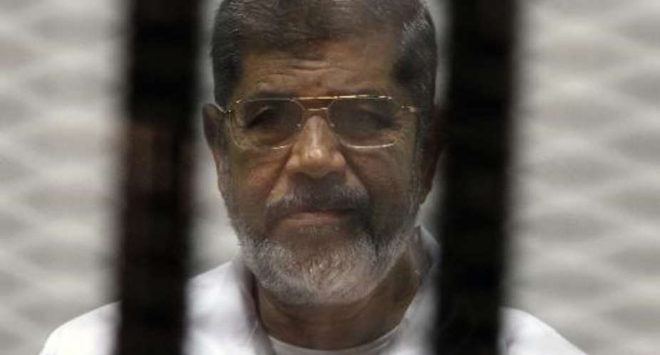 Egypt's deposed Islamist president Mohamed Morsi waves from inside the defendants cage during his trial at the police academy in Cairo on January 8, 2015.  By  AFPFile