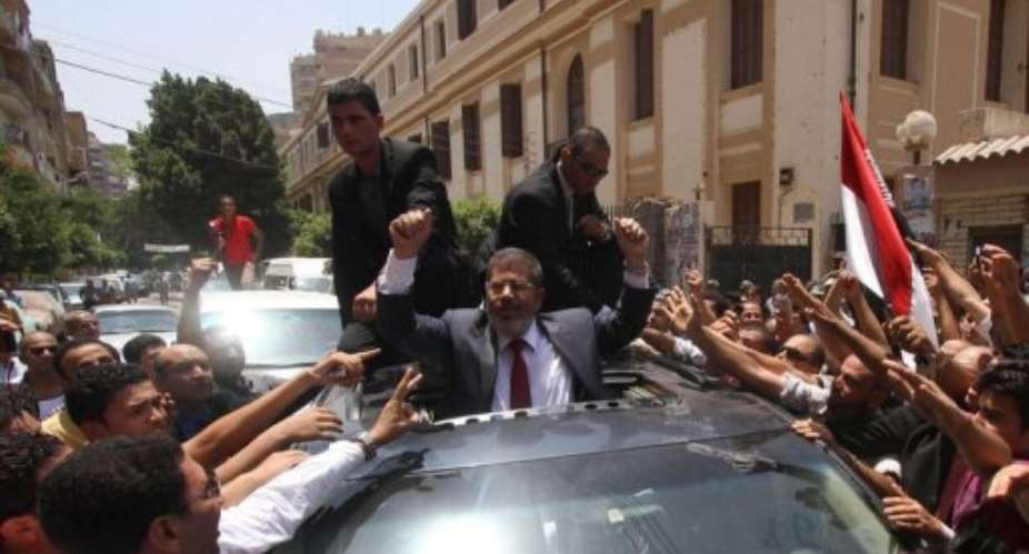 Egyptian Muslim Brotherhood candidate Mohammed Mursi C waves to his supporters as he leaves a polling station.  By  AFP