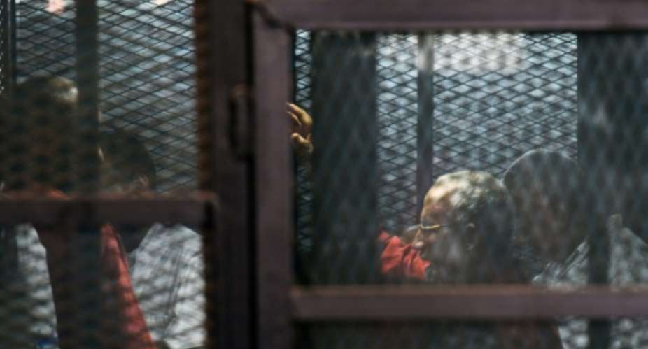 Egyptian Muslim Brotherhood leader Mohamed Badie 2nd-R stands behind bars during a trial in Cairo on August 22, 2015.  By Mohamed el-Shahed AFP