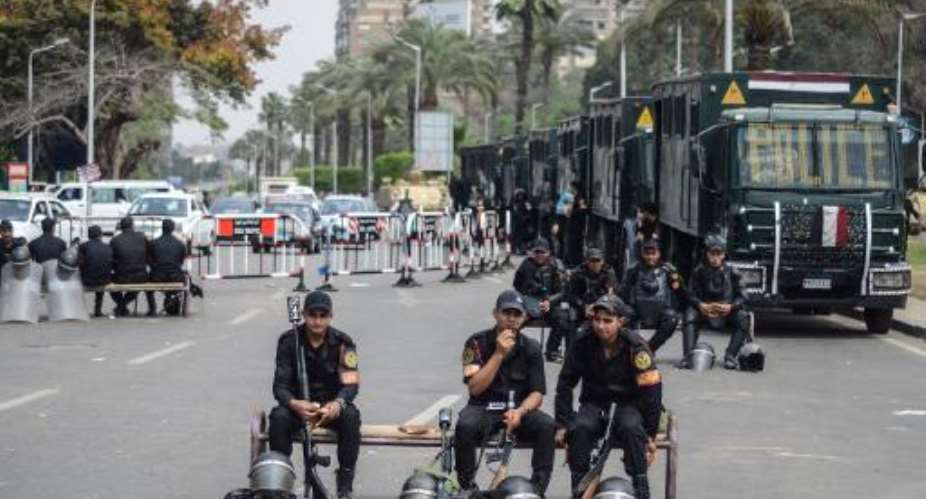 Egyptian policemen sit on benches on a street in Cairo on April 16, 2014.  By Mohamed el-Shahed AFP