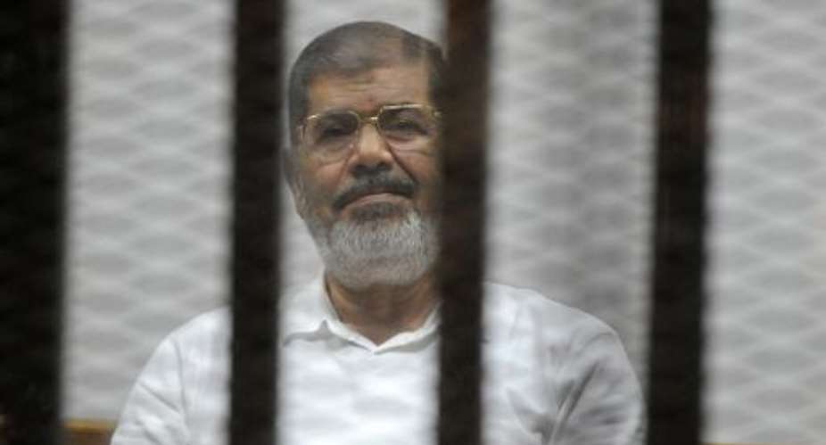 Egypt's deposed Islamist president Mohamed Morsi sists behind the defendants cage during a trial at the police academy court in Cairo on November 5, 2014.  By Str AFPFile