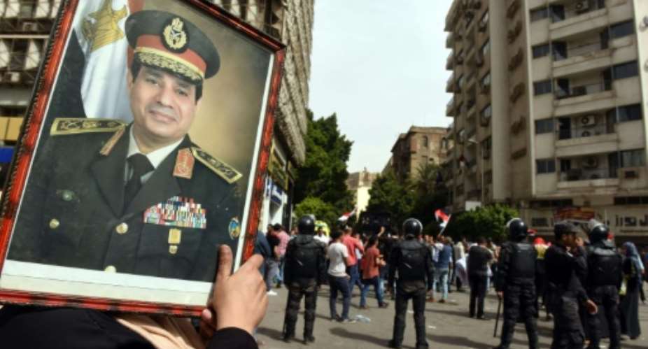 A supporter of President Abdel Fattah al-Sisi waves a of portrait of him as protesters gather outside the Journalists' Syndicate headquarters in Cairo on May 4, 2016.  By Mohamed El-Shahed AFP