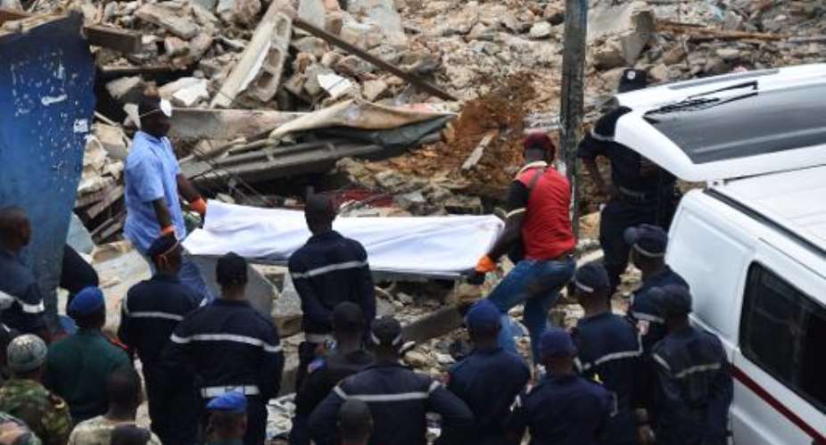 Rescuers carry the body of a man after a building collapsed during demolition work on November 5, 2014 in the Attecoube neighbourhood of Abidjan.  By Sia Kambou AFP