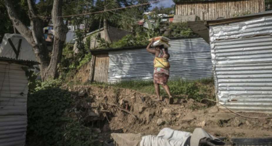 ENkanini resident Thulisile Ntobela carries donated food through the informal settlement where she put up a shack.  By Guillem SARTORIO (AFP)