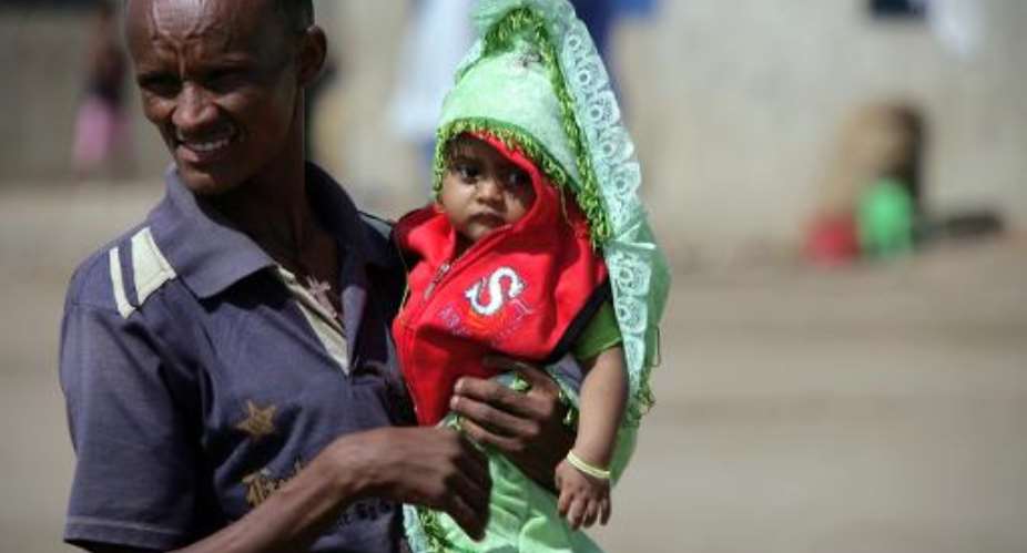 An Eritrean refugee holds his child at Sudan's Shagarab refugee camp in Kassala on January 12, 2012.  By Ashraf Shazly AFPFile