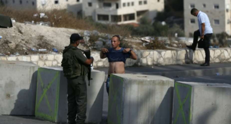 An Israeli border guard inspects a Palestinian man at a newly erected checkpoint at the exit of the east Jerusalem neighborhood of Issawiya on October 19, 2015.  By Ahmad Gharabli AFP