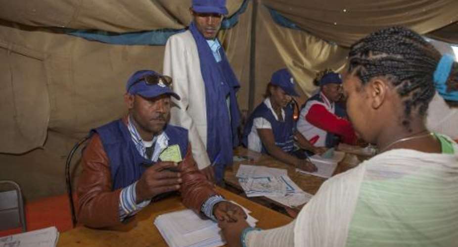 Ethiopian Electoral Board employees stamp a voter's hand with indelible ink at a polling station in Addis Ababa on May 24, 2015.  By Zacharias Abubeker AFPFile