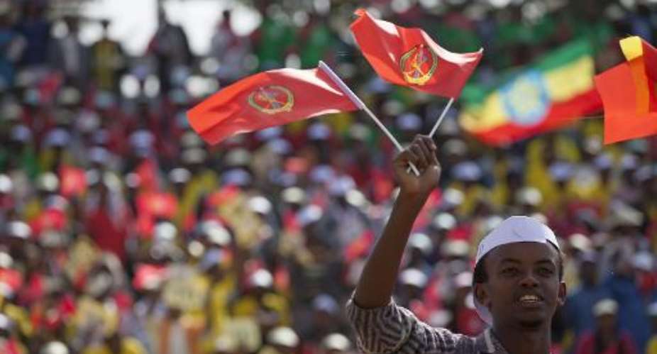 A young man waves the ruling party Ethiopian People's Revolutionary Democratic Front EPRDF flag in front of a large crowd during an election EPRDF rally in Addis Ababa on May 21, 2015.  By Zacharias Abubeker AFPFile