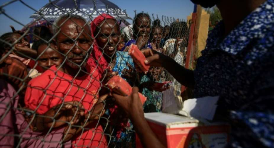 Ethiopian refugees who fled fighting in the Tigray region receive food at the 'Village 8' reception center in Sudan's eastern Gedaref state.  By ASHRAF SHAZLY AFP