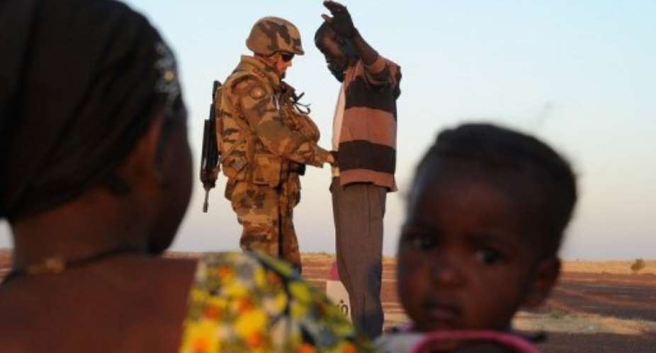 A woman and child watch a French soldier at a check point frisking a man trying to enter Gao, Mali on February 14, 2013.  By Pascal Guyot AFPFile