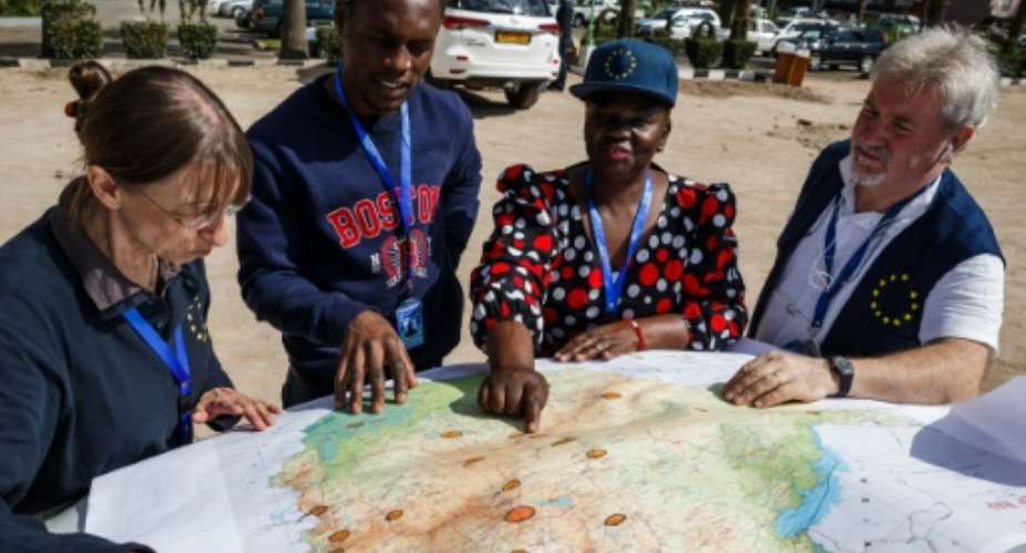 EU observers study a map upon arrival, as part of their deployment in the European Union Election Observation Mission.  By Jekesai NJIKIZANA AFP