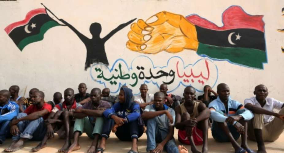 Illegal migrants sit in front of a painted wall on May 19, 2016 at the Abu Salim detention centre in the Libyan capital Tripoli.  By Mahmud Turkia AFPFile