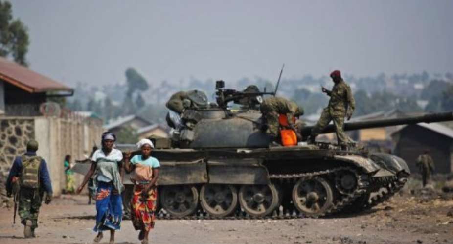 Two Congolese women walk past a government army tank in Munigi, on the outskirts of Goma on July 15, 2013.  By Phil Moore AFPFile
