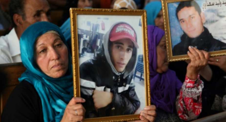 Families of people killed during protests that led to Tunisia's revolution hold photographs of their relatives inside a courthouse in the central city of Kasserine on July 13, 2018.  By HATEM SALHI AFP