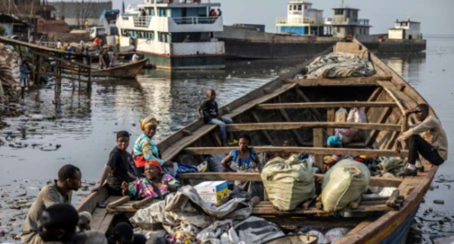 Families wait in a boat with their belongings on the shores of Lake Kivu in Bukavu as thousands flee the conflict.  By Luis TATO (AFP/File)