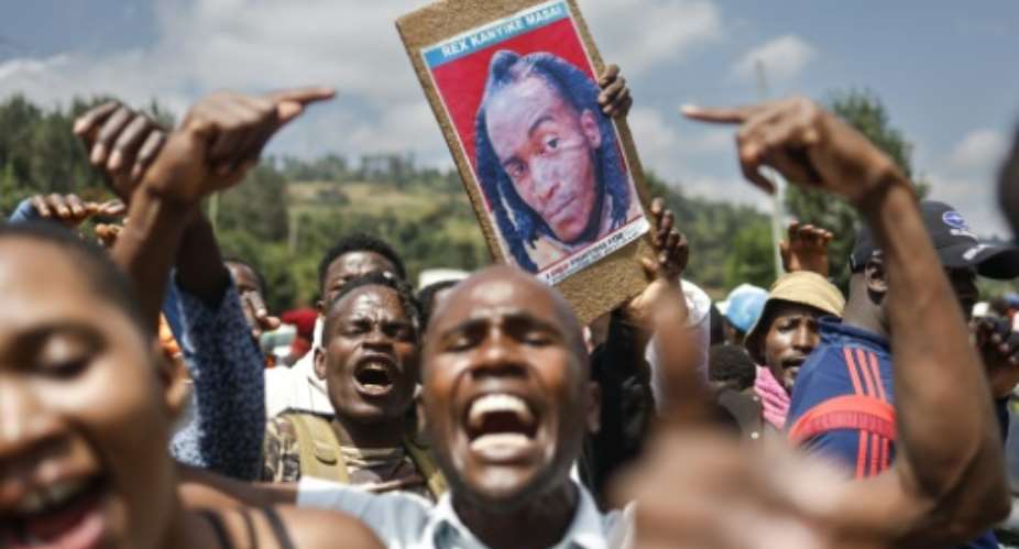 Family, friends and fellow protesters carry a photo of Rex Masaiwho was shot by the police.  By SIMON MAINA (AFP/File)