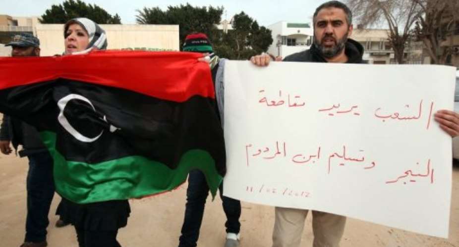 A Libyan protester holds her national flag next to a demonstrator holding a sign calling to cut ties with Niger.  By Mahmud Turkia (AFP)