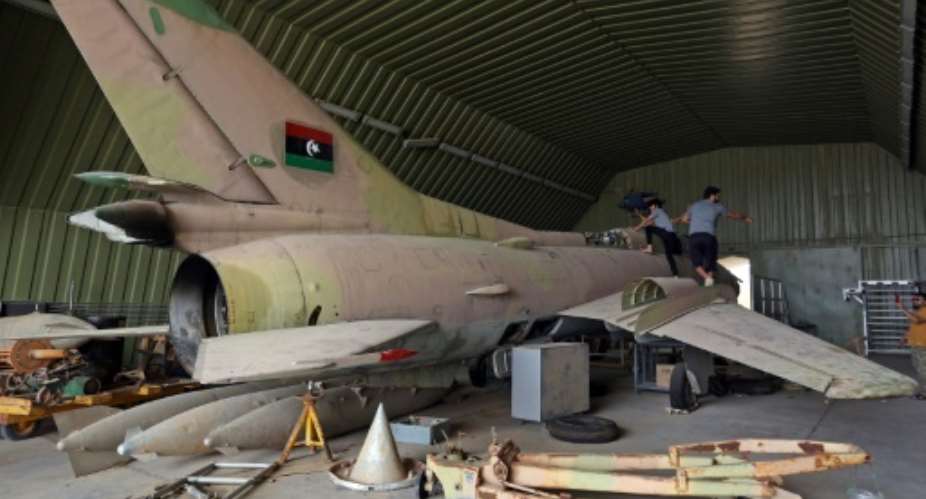 Fighters loyal to Libya's UN-recognised Government of National Accord GNA climb over a partially disassembled MiG 23 aircraft, after seizing Al-Watiya airbase  southwest of the capital Tripoli, on May 18, 2020..  By Mahmud TURKIA AFPFile