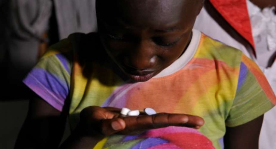 Claudia Aulo, a 13-year-old Kenyan girl living with AIDS and who lost both parents to the disease, takes her drugs at grandmother's house in Ndiwa.  By Simon Maina AFP