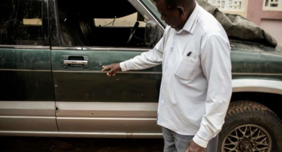 Filipe Mahanjane points to bullet holes in the car where election observer Anastacio Matavele was slain in Xai-Xai, Mozambique.  By GIANLUIGI GUERCIA AFP