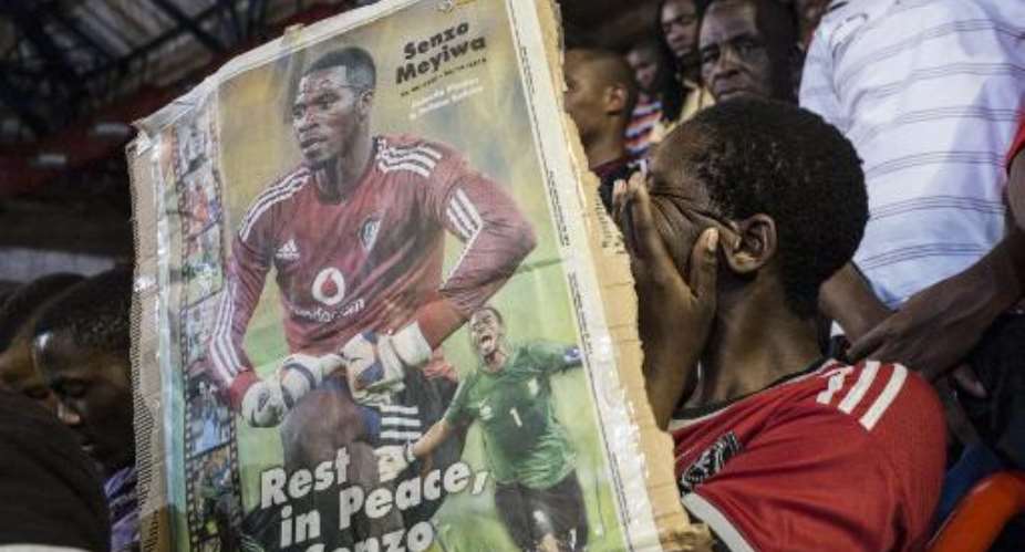 A fan cries holding a portrait of the slain Bafana-Bafana and Orlando Pirates captain Senzo Meyiwa during a memorial service in Johannesburg on October 30, 2014.  By Marco Longari AFP