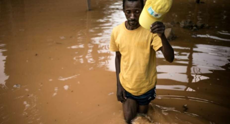 Fisherman Edouard walks among the flooded ruins of his house in Bangui. I don't have the money to rebuild it, he said.  By FLORENT VERGNES AFP