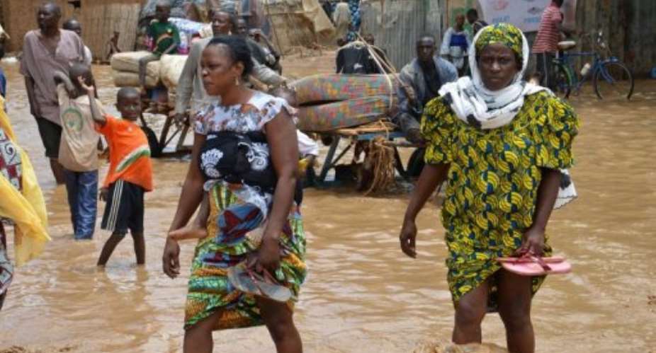 Residents walk in floodwaters as they evacuate Niamey after their homes were destroyed by floods on August 19, 2012.  By Boureima Hama AFPFile